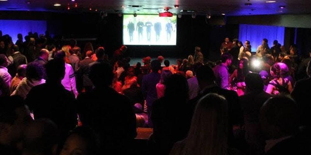 Crowd in a dark room with a screen.